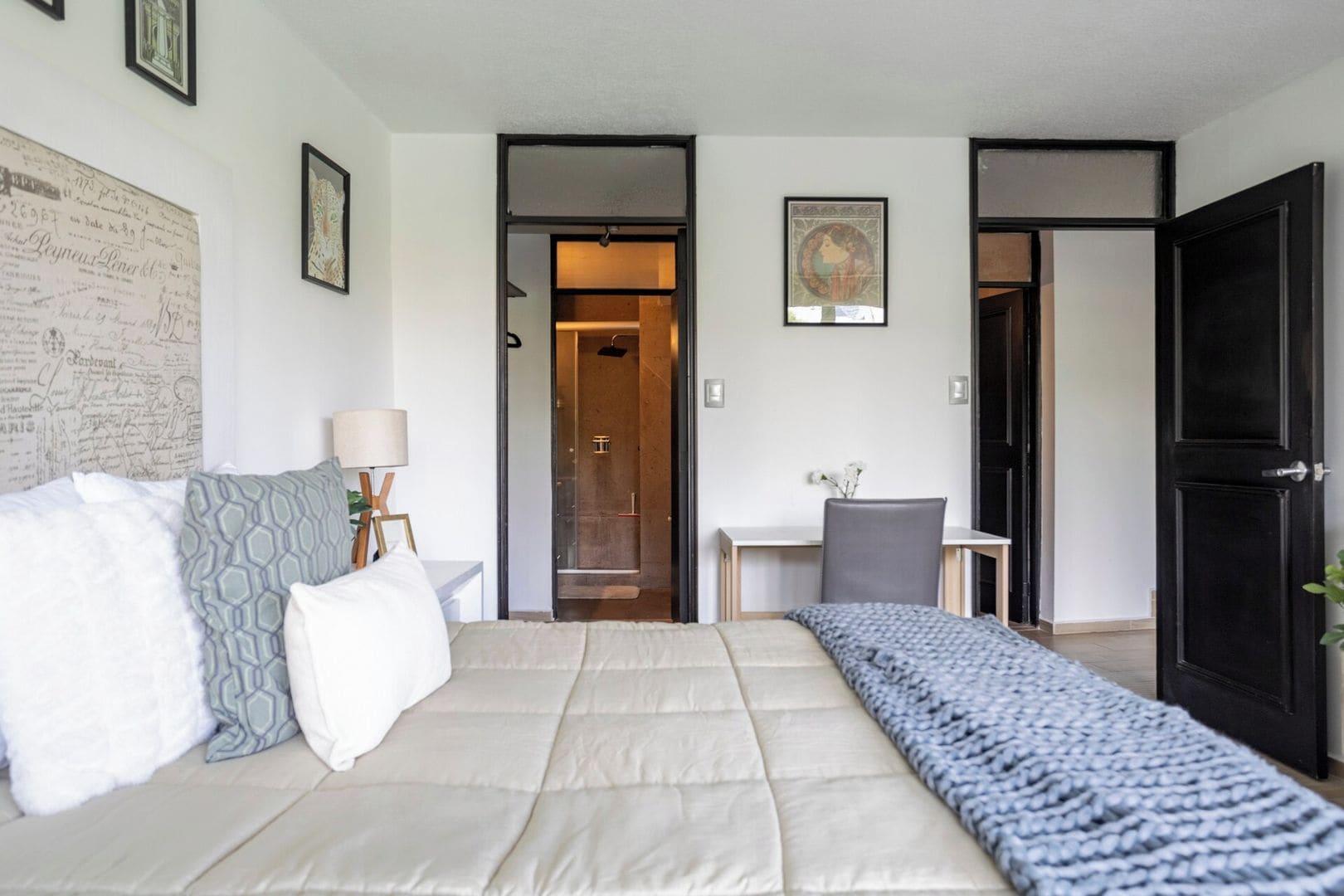 A hotel room with a bed, a desk, and a wardrobe.