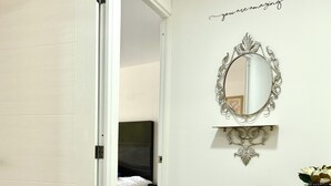 A hotel room with a bed, a mirror, and a wall with a motivational quote.