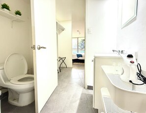 Une salle de bain comprenant des toilettes, un lavabo et un espace douche.