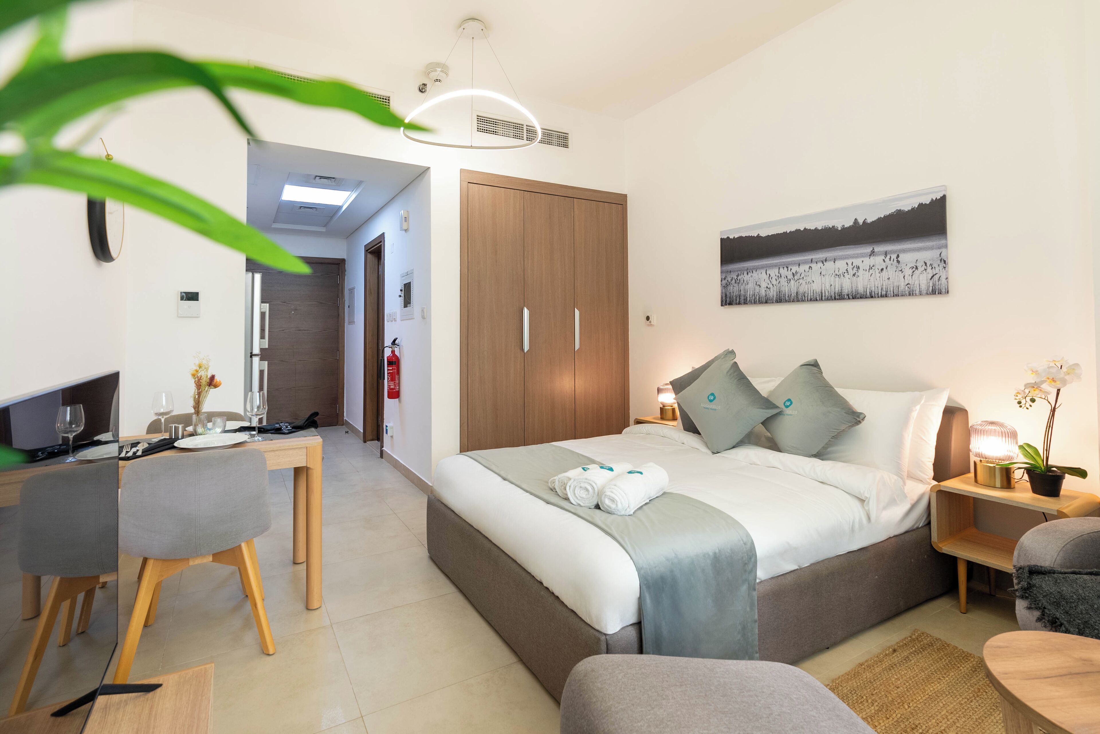 A modern bedroom with a large bed, bedside tables, a desk, and a dining area.