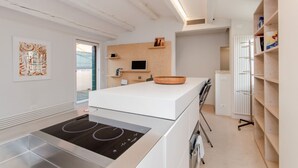 Eine moderne Küche mit Einbauherd, weißen Schränken und einer Holzausziehtafel.