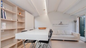 Ein modernes Wohnzimmer mit einem weißen Sofa, einem Esstisch mit Stühlen und einem Bücherregal.