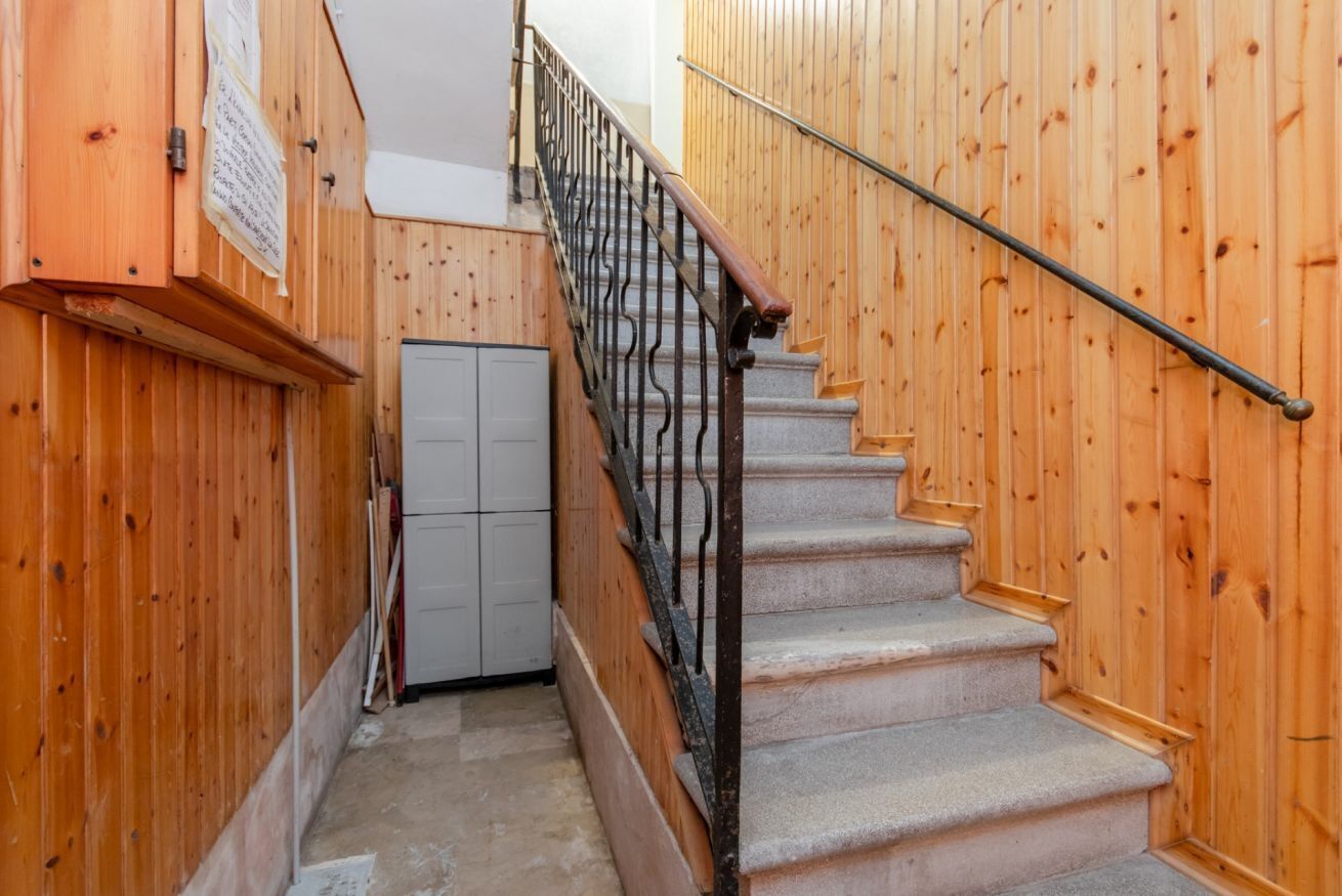 A wooden staircase with a metal handrail, a white door, and a wooden wall with a bulletin board.