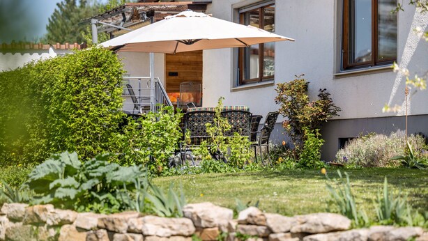 Ein Haus mit Garten, Gartenmöbeln und einer Steinmauer.