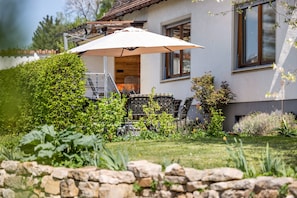 A house with a garden, outdoor furniture, and a stone wall.