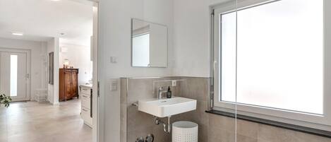 A modern bathroom with a sink, mirror, and window.