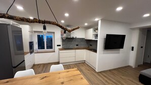 Eine moderne Küche mit weißen Schränken, einem Holzespeisetisch und einem an der Wand befestigten Fernseher.