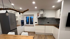 Eine moderne Küche mit Holztisch, weißen Schränken und einem eingebauten Backofen.