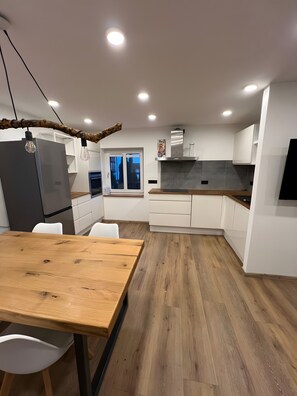 Eine moderne Küche mit Holztisch, weißen Schränken und einem eingebauten Backofen.