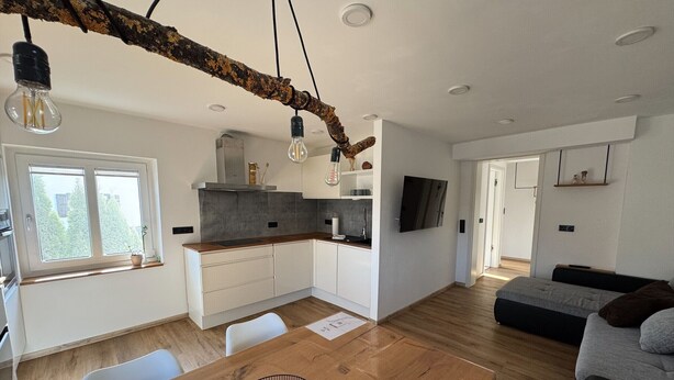 Eine moderne Küche mit Holztischplatte, weißen Schränken und einem Essbereich mit einem Holztisch und Stühlen.
