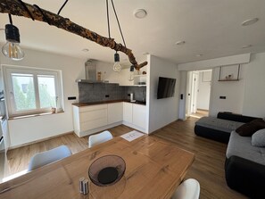 Et moderne køkken med træbordplade, hvide skabe og et spiseområde med et træbord og stole.
