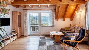 Een gezellige woonkamer met een houten plafond, een televisie, een bank, een stoel en een tafel.