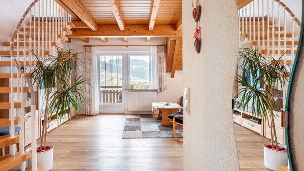 Een houten interieur met een trap, potplanten en een tafel.