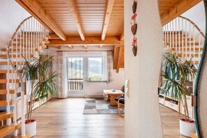 A wooden interior with a staircase, potted plants, and a table.