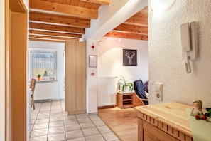 Quarto com vigas de madeira, radiador, planta e um certificado emoldurado na parede.