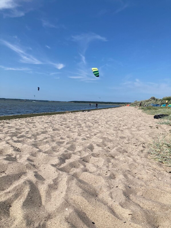 A beach with sand, water, and a kite. - Surf Bungalow in Prime Location with Sea View, Private Terrace, and Wi-Fi (Am salzhaff)