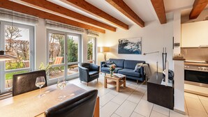 Ein modernes Wohnzimmer mit einer Couch, einem Esstisch und einer Küchenzeile.