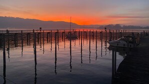 A pier extending into calm water with a sunset in the background. - Aura Upper Floor Holiday Home with Lake View, Alpine Panorama, Balconies, Garden & Wi-Fi (Bodman-Ludwigshafen)