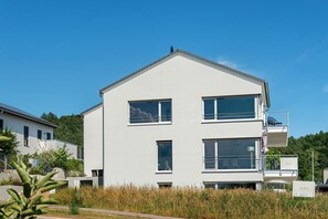 A modern two-story building with large windows, a balcony, and a sign labeled 'AURA'. - Aura Apartment with Terrace, Garden and Wi-Fi (Bodman-Ludwigshafen)