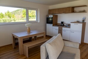 A compact kitchen with a built-in oven, a coffee maker, and a window overlooking greenery.
