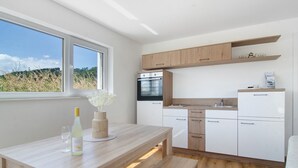 Een moderne keuken met een houten tafel, witte kasten en een ingebouwde oven.