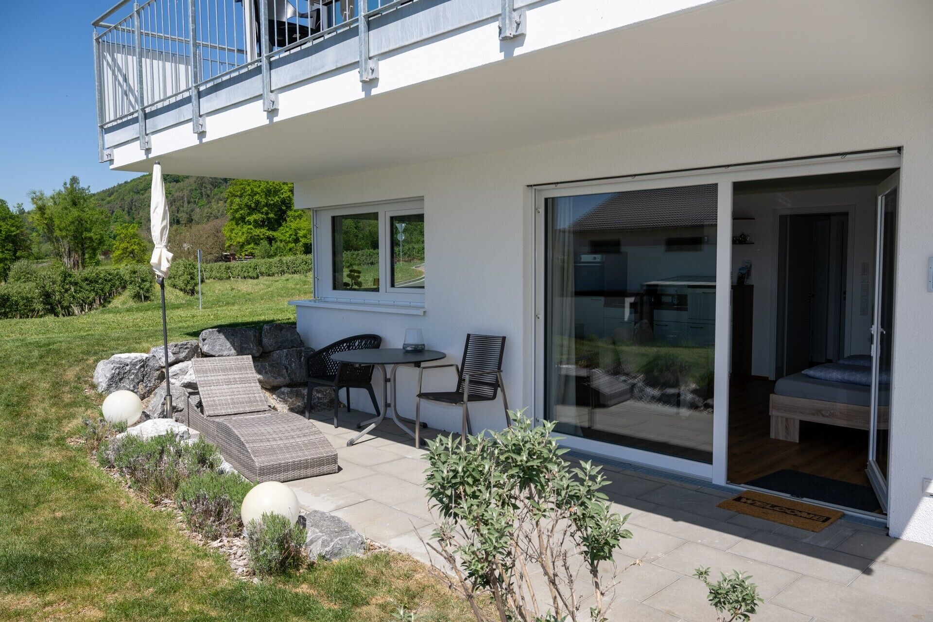 Une maison moderne dotée d’un patio, d’un coin repas et d’une porte-fenêtre coulissante donnant accès à une chambre.