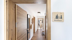 Un couloir intérieur en bois, avec une porte en bois, un banc et une enseigne indiquant « Waldhaus ».