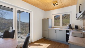 A modern kitchen with a wooden ceiling, large windows, and a view of the outdoors. - Holiday Apartment 'Bauernhof' with Mountain View, Private Terrace and Wi-Fi (Schmallenberg)