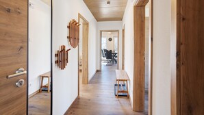 A hallway with wooden flooring, a wooden door, a bench, and a wall-mounted light fixture. - Holiday Apartment 'Bauernhof' with Mountain View, Private Terrace and Wi-Fi (Schmallenberg)