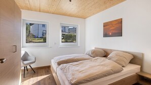 A bedroom with two windows, a bed, a chair, and a painting. - Holiday Apartment 'Bauernhof' with Mountain View, Private Terrace and Wi-Fi (Schmallenberg)