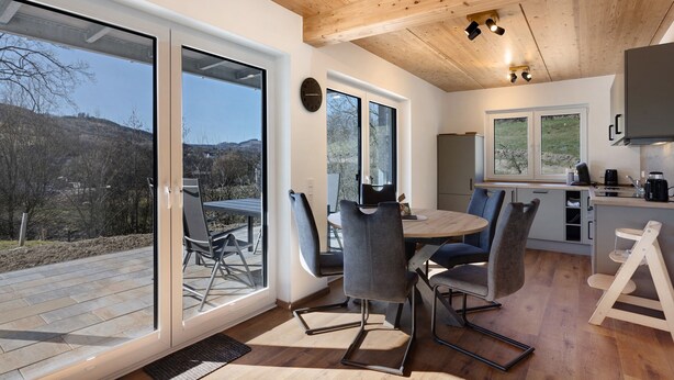 A modern kitchen with a wooden ceiling, large windows, and a dining area with chairs and a table. - Holiday Apartment 'Bauernhof' with Mountain View, Private Terrace and Wi-Fi (Schmallenberg)