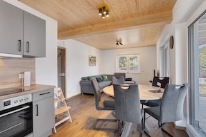 Une cuisine moderne dotée d’appareils électroménagers intégrés, un coin repas avec une table ronde et des chaises, et une grande fenêtre offrant une vue sur l’extérieur.