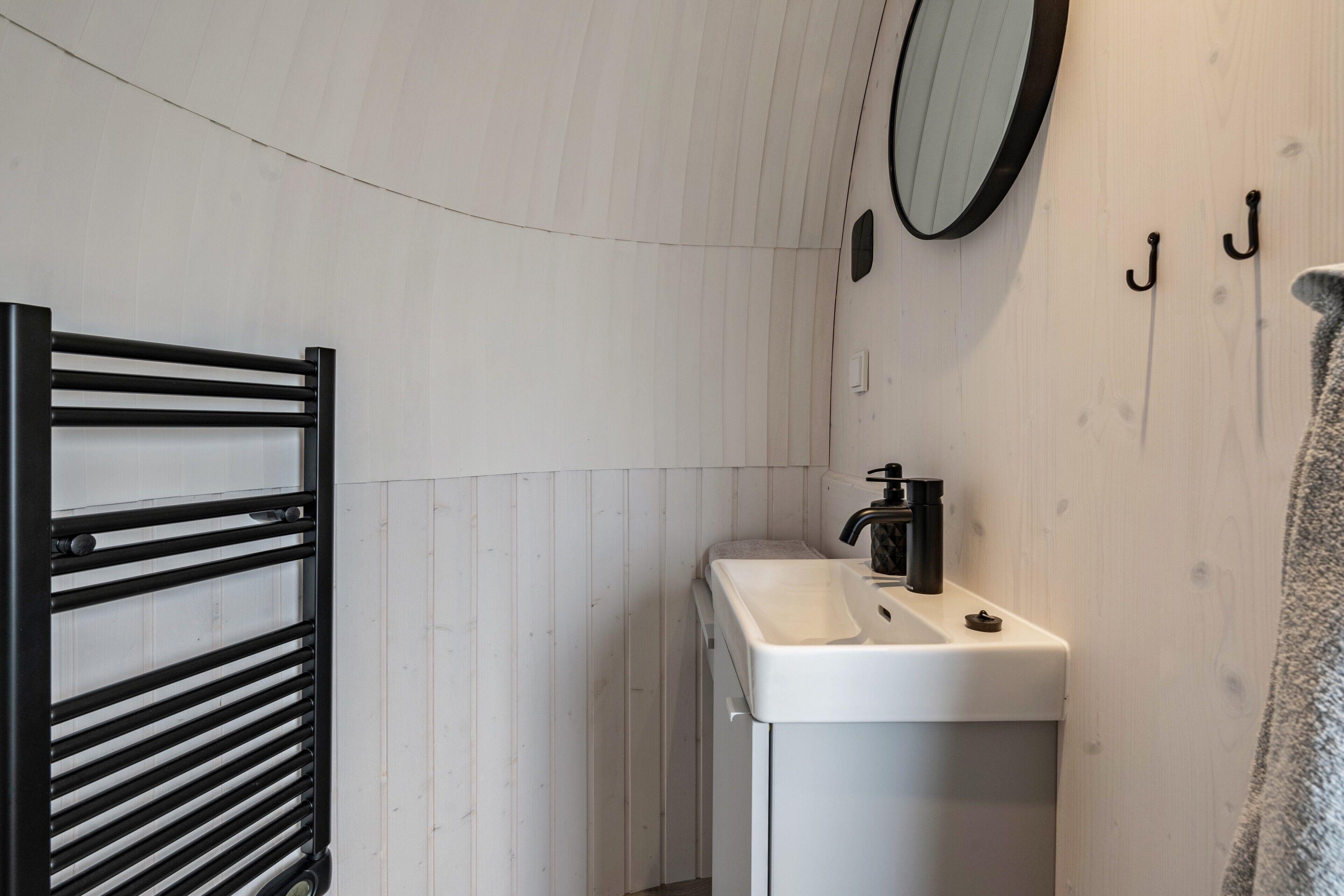 A bathroom with a white sink, black faucet, and a towel rack.