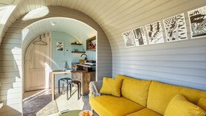 Un intérieur chaleureux avec un canapé jaune, un coin repas et une cuisine.