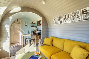 Un interior acogedor con un sofá amarillo, una zona de comedor y una cocina.