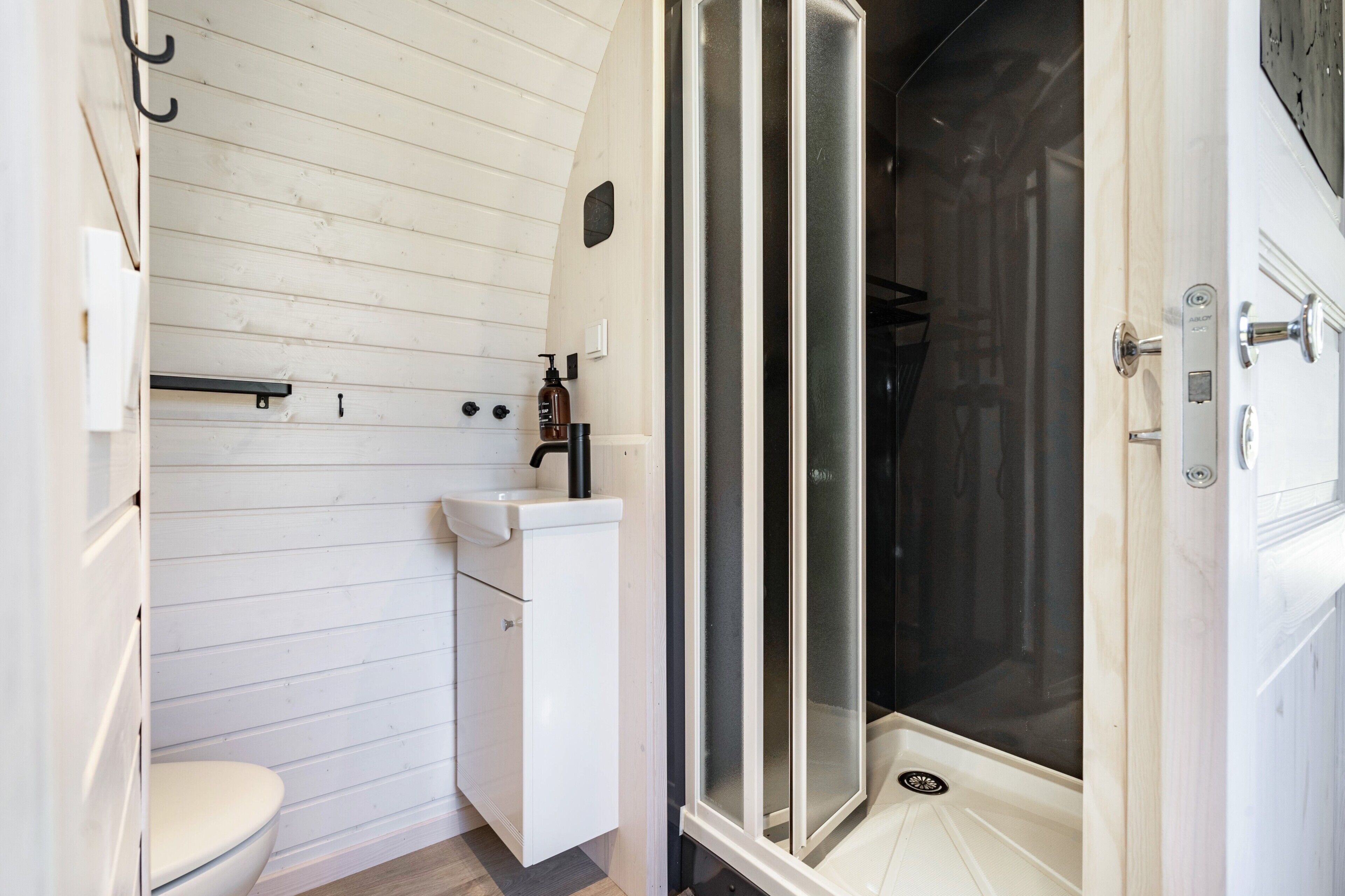 Une salle de bain avec un lavabo blanc, des toilettes et une douche fermée par une paroi de verre.