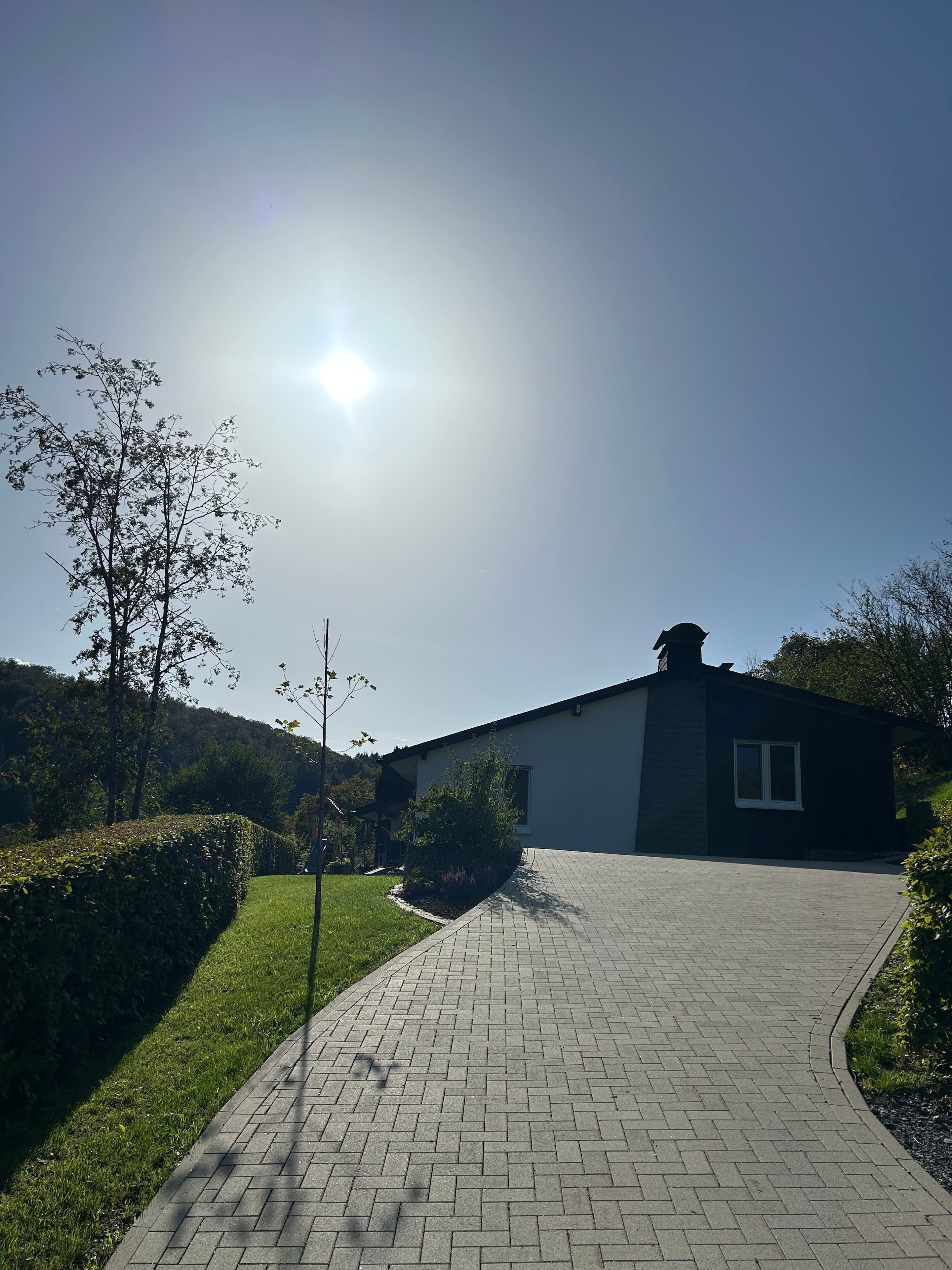 A paved pathway leading to a modern building with a flat roof and a window.