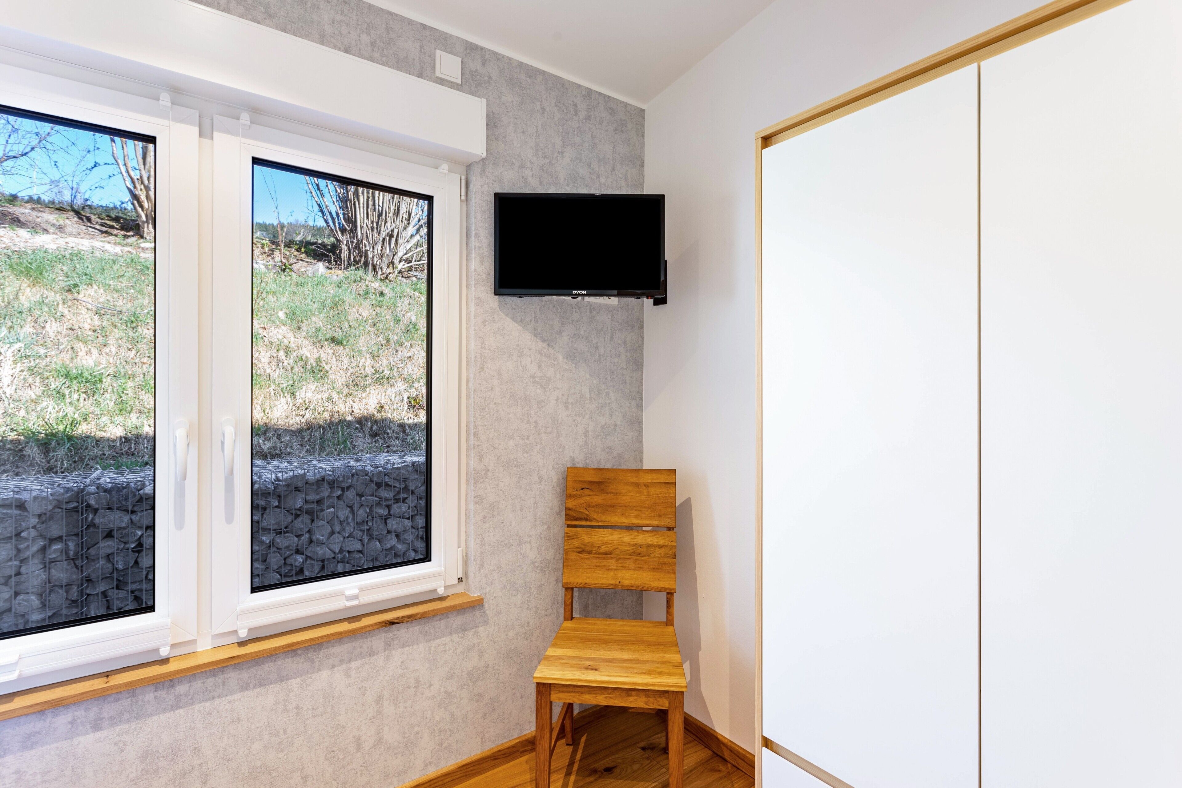 A room with a window, a television, and a wooden chair.