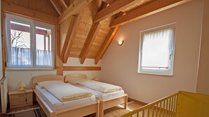 A room with two beds, a crib, wooden beams, a window, and a radiator. - Apartment 'C' with Lake View, Balcony and Wi-Fi (Meersburg)