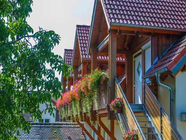 Una hilera de casas de madera con tejados de tejas y balcones decorados con flores.