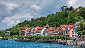 A waterfront hotel with traditional architecture, a pier, and a forested hillside. - Apartment 'C' with Lake View, Balcony and Wi-Fi (Meersburg)
