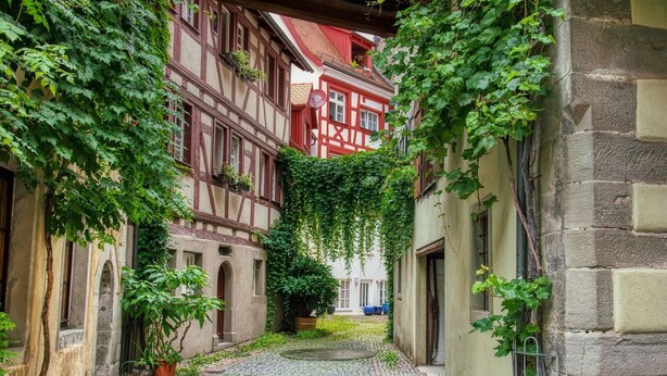 A narrow cobblestone alley with traditional half-timbered houses, one with red accents and ivy. - Apartment 'A' with Lake View, Balcony and Wi-Fi (Meersburg)