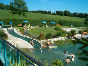 A water park with a slide, a pool, and a grassy area with benches.