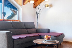 Un salon moderne avec un canapé gris, une table basse ronde en bois et un lampadaire.