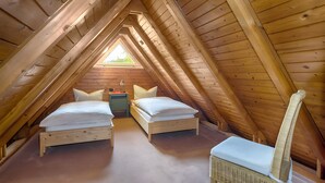 A small, cozy attic bedroom with two beds, a nightstand, and a chair. - Holiday Home 'Häusle Nr 2' with Shared Garden and Balcony (Titisee-Neustadt)