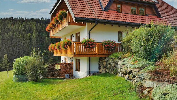 A two-story house with a red-tiled roof, wooden balconies with flower boxes, and a stone wall. - Holiday Home 'Häusle Nr 2' with Shared Garden and Balcony (Titisee-Neustadt)