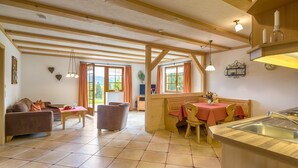 A spacious living area with a sofa, dining table, and kitchen area with a sink. - Apartment 'Birke' with Private Terrace, Shared Garden and Wi-Fi (Titisee-Neustadt)