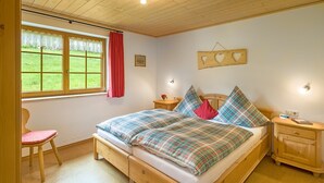 Un dormitorio con una cama de madera, una ventana con vistas, una mesita de noche y una silla.