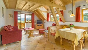 A cozy room with a wooden ceiling, a dining table, a sofa, and a television. - Apartment 'Fichte' with Shared Garden, Balcony and Wi-Fi (Titisee-Neustadt)