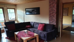 Una sala de estar con un sofá de color oscuro, una mesita de madera y una alfombra roja.